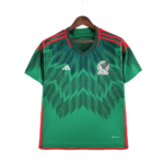 Green Mexico national team jersey with red trim, hanging on a wooden hanger, Adidas logo visible on the chest edge