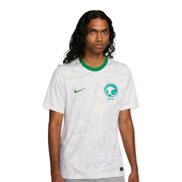 Person with long dark hair wearing a white patterned jersey with a green collar, facing forward against a white background.