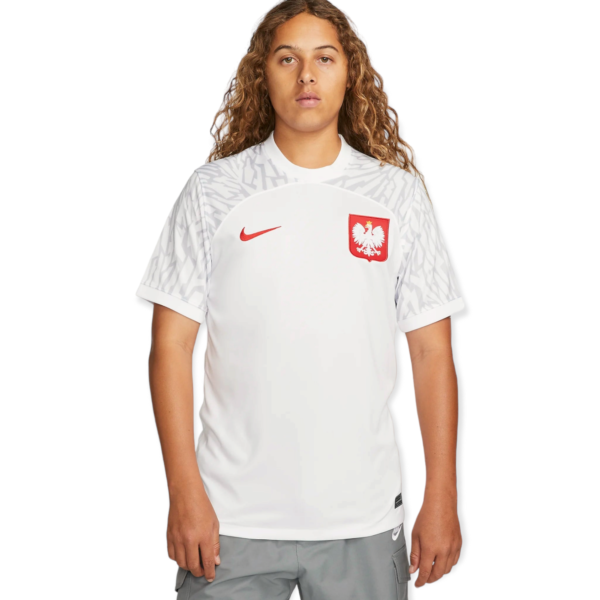 Person facing camera wearing a white athletic jersey with a gray geometric pattern and the Polish eagle crest on the chest; plain white background.”