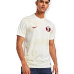 Man wearing a white patterned soccer jersey with a red crest on the chest and a red Nike swoosh.