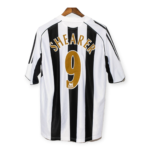 Back view of a black-and-white striped soccer jersey on a wooden hanger, with the name 'SHEARER' and number '9' in gold letters on the back.