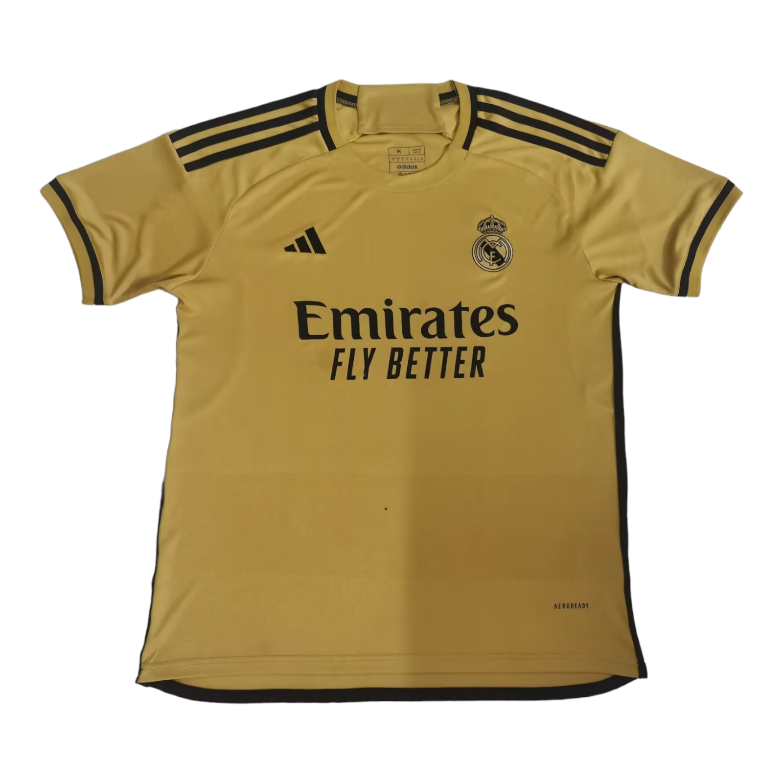 PhotoRoom-20230624_091348_a74649a0-ef44-4495-a41d-c4ef360c9430 Gold Real Madrid soccer jersey with Emirates Fly Better sponsor, Adidas logo, and club crest on the chest, featuring black shoulder stripes.