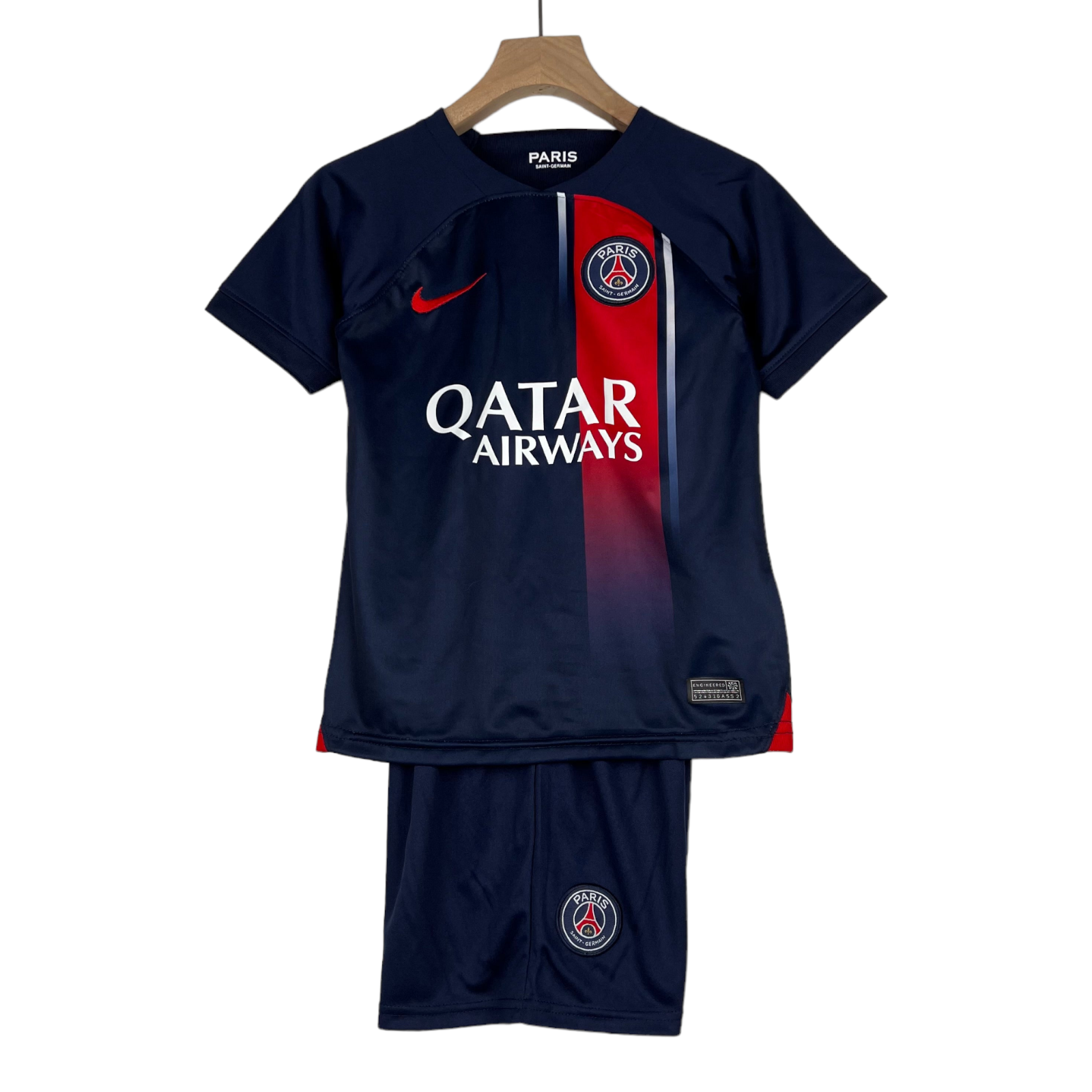 PhotoRoom-20230629_163217_4606c2e3-448f-4c35-8a42-95ee1d3ffb5b Navy Paris Saint-Germain football jersey with a red vertical stripe, sponsor logo Qatar Airways, and crest on the chest, hanging on a wooden hanger.