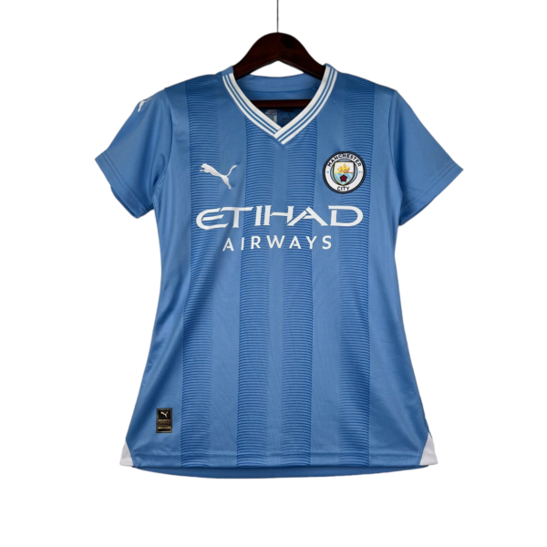 Blue Manchester City football jersey on a wooden hanger, showing the club crest, Puma logo, and Etihad Airways sponsor.