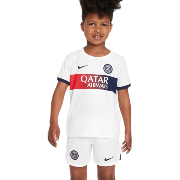 Child wearing a white PSG kit with Qatar Airways sponsor, Nike logo, and club crest visible on chest and shorts.