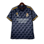Real Madrid navy away jersey on hanger with Adidas logo and Emirates Fly Better slogan, yellow shoulder stripes, patterned design