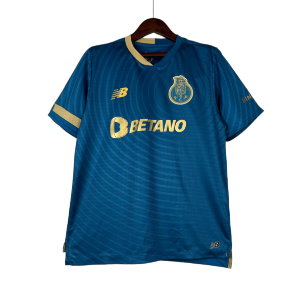 Blue football jersey with gold trim on a hanger, featuring a club crest on the chest and New Balance logo, sponsorship by Betano.