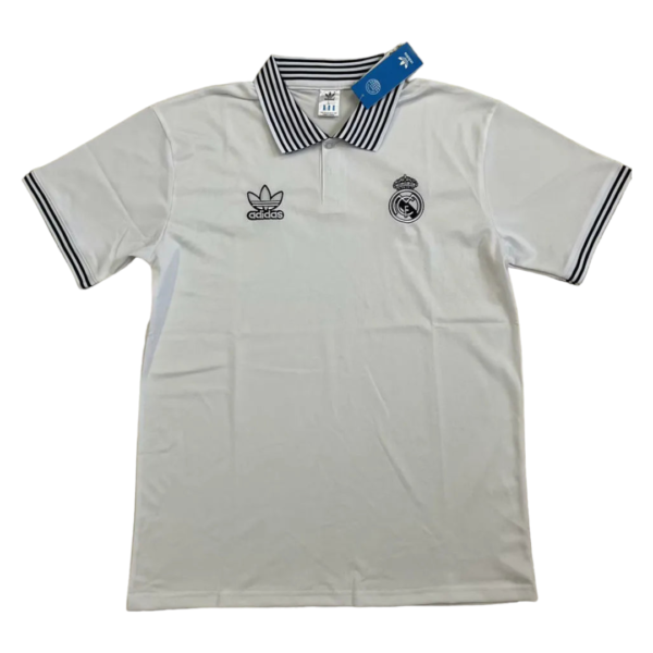 White polo shirt with Real Madrid crest and Adidas logo on the chest, black striped collar and sleeve cuffs, tag attached