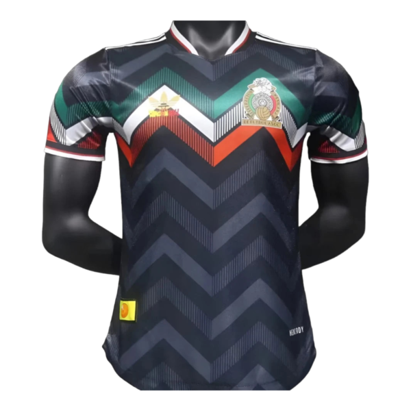 Dark chevron-patterned soccer jersey with green/teal and orange chevrons and a crest on the left chest.