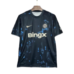 Dark blue Chelsea FC jersey with blue splatter pattern, Nike swoosh, sponsor BingX, hanging on a wooden hanger