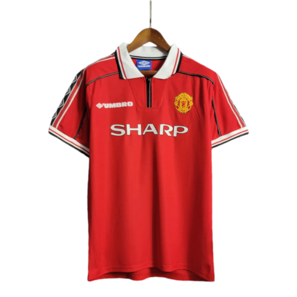 Manchester United red home jersey on a hanger with white collar and SHARP sponsor logo across the chest, crest on the left.