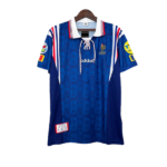 Blue Adidas rugby jersey on a hanger with white collar and red-white-blue trim, featuring patches on sleeves and chest badges.