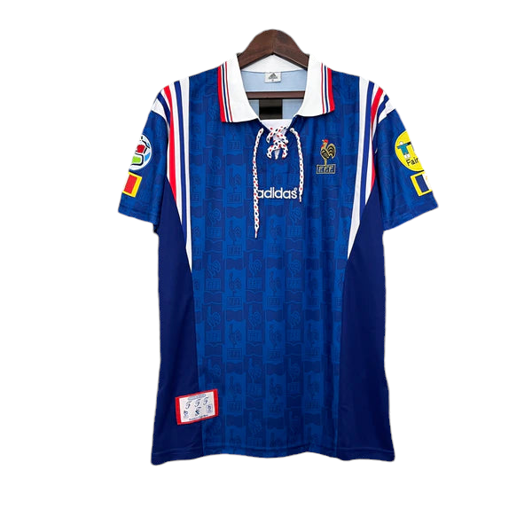 Blue Adidas rugby jersey on a hanger with white collar and red-white-blue trim, featuring patches on sleeves and chest badges.