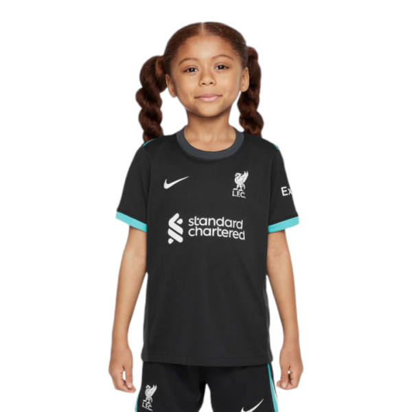 Young girl in a black Liverpool FC training jersey with standard chartered sponsor logo and crest, teal trim on sleeves, standing and facing forward to camera.