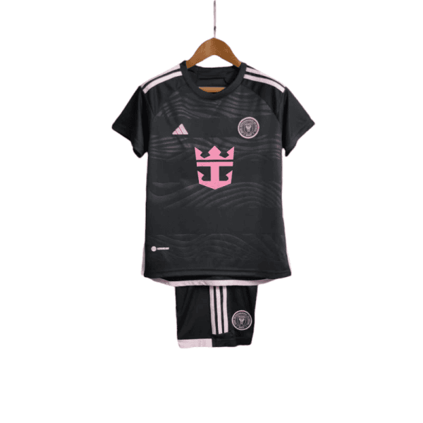 Black soccer kit with pink accents (jersey and shorts) hanging on a wooden hanger; pink crest and stripes visible on the chest and legs.