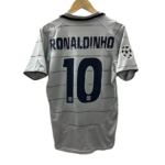 Photoroom-20240820-231158 | UAE SPORT STORE Gray soccer jersey hung on a wooden hanger, back shows 'RONALDINHO' and number 10 with a Champions League badge on the sleeve.