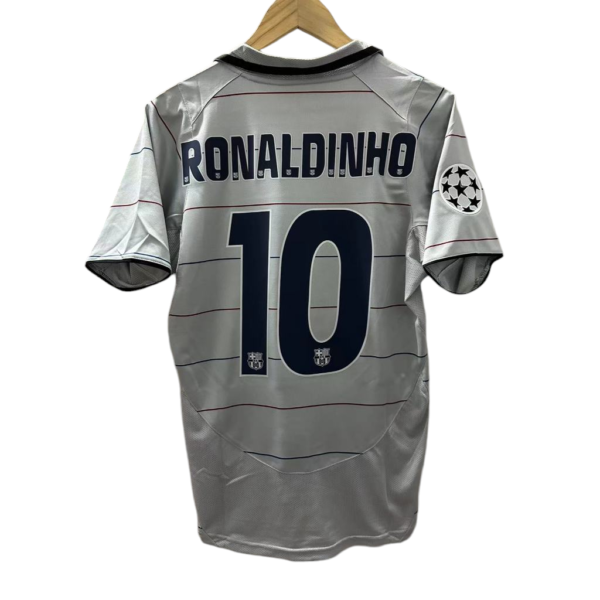 Gray soccer jersey hung on a wooden hanger, back shows 'RONALDINHO' and number 10 with a Champions League badge on the sleeve.