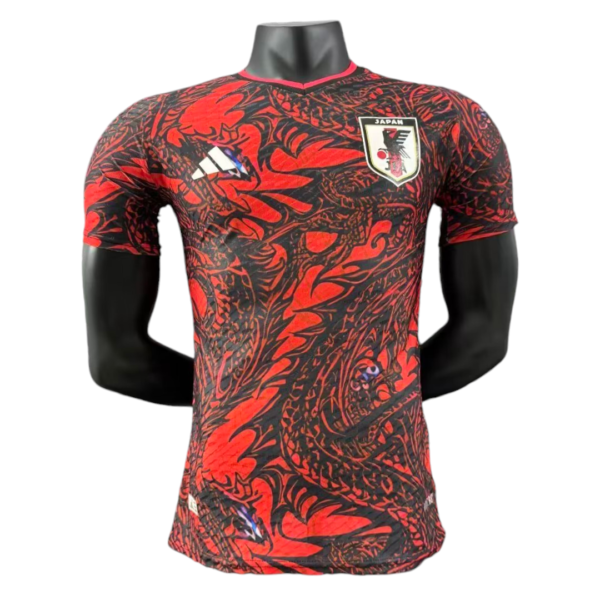Red and black patterned Japan football jersey with crest on the chest and Adidas logo on the other side.