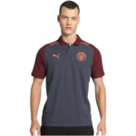 Male model wearing a navy polo shirt with maroon sleeves and collar, featuring an orange Puma logo and Manchester City crest on the chest.