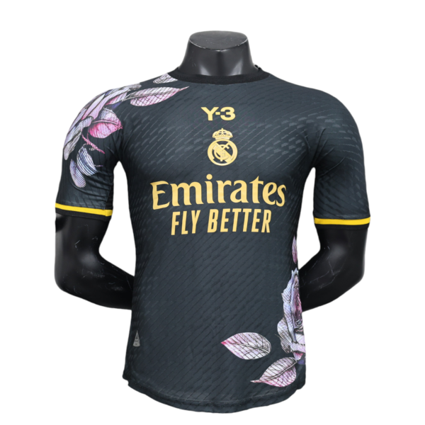 Mannequin torso wearing a dark Real Madrid football jersey with gold Emirates sponsor text and crest, accented by a pink leaf pattern on the chest and sleeves.