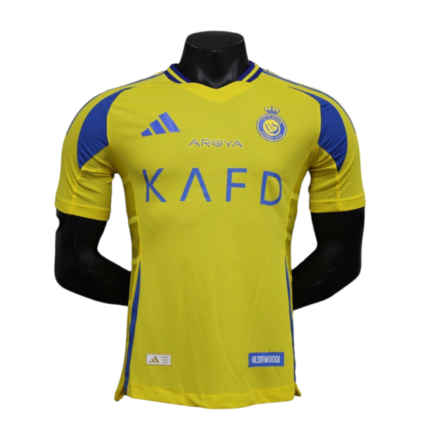 Yellow soccer jersey on a mannequin, blue shoulder panels, crest on left chest and 'K A F D' across front in blue text, ALDAWOODI sponsor patch at bottom right