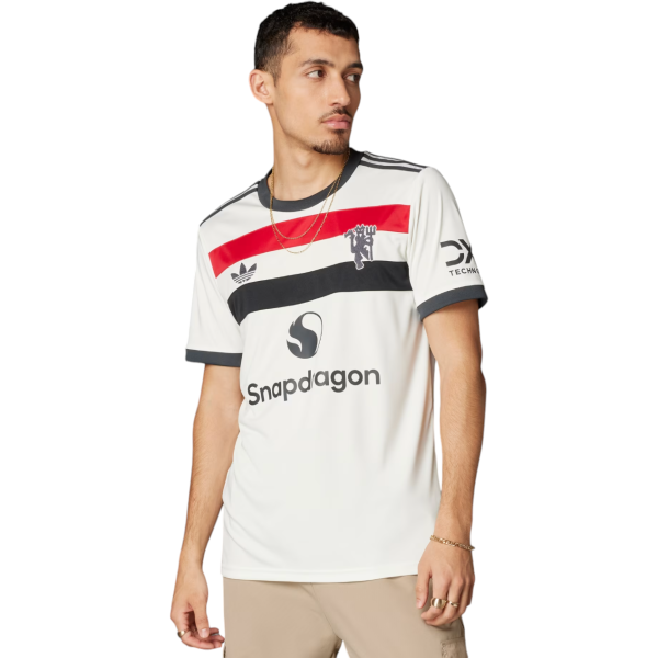 Male model wearing a white striped sports jersey with red and black bands, Adidas-style stripes, and Snapdragon logo on chest, beige pants visible