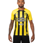 Man wearing a yellow and black striped soccer jersey with Arabic script and sponsor logos, facing forward.
