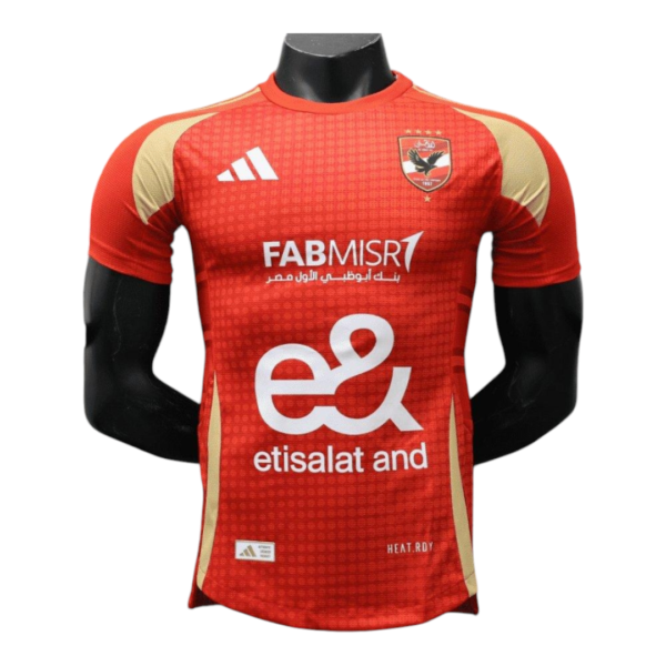 Red soccer jersey on a mannequin with beige shoulder panels and white sponsor logos on the chest (Etisalat and FABMISR).