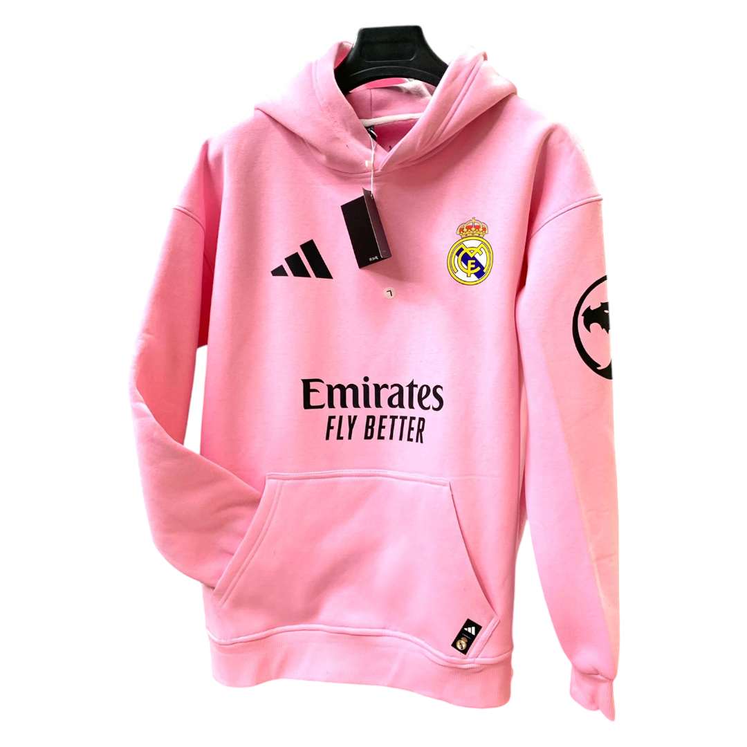 Photoroom-20250110-201344 Pink Real Madrid hoodie with Emirates Fly Better branding, Adidas logo, front pocket, hanging on a black hanger.