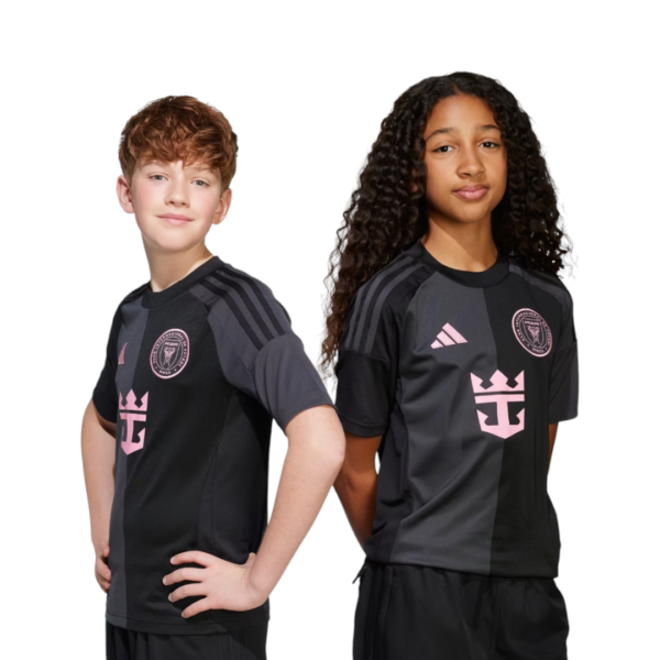 Two kids posing in black and gray soccer jerseys with pink logos, standing back-to-back with hands on hips on a white background.