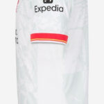 QRQCzZjsfU84Kcq_89c4ed71-e12d-496a-911b-df102dd9156a | UAE SPORT STORE Side view of a white sports jersey with red trim and Expedia logo on chest, light camouflage pattern behind.