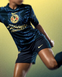 QVsY3zy1SvWxOXI | UAE SPORT STORE Athlete in a navy soccer jersey mid-kick, with gold crest and Nike swoosh visible against a yellow-green background into focus on the upper body and leg actions.