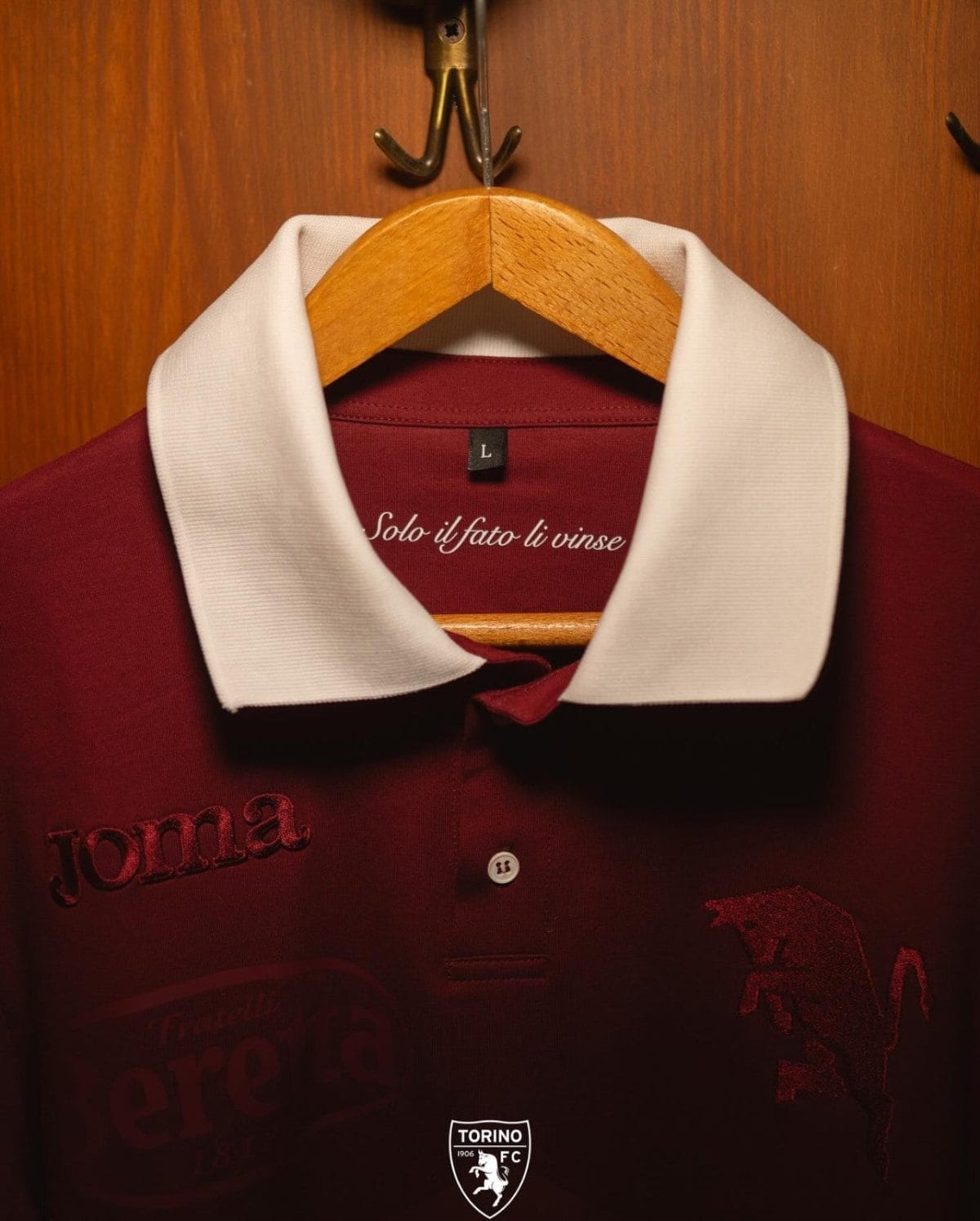Maroon polo with a white collar hanging on a wooden hanger in a wardrobe, showing a size L tag and Torino FC crest at the bottom.