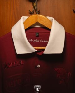 Maroon polo with a white collar hanging on a wooden hanger in a wardrobe, showing a size L tag and Torino FC crest at the bottom.