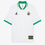 White soccer jersey with green collar and cuffs and thin blue vertical pinstripes; features a crest on the left chest and a sponsor logo on the right chest, plus a gold patch near the bottom hem.