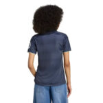 Person viewed from the back wearing a navy short-sleeve polo shirt and blue jeans, with curly hair. (informative)