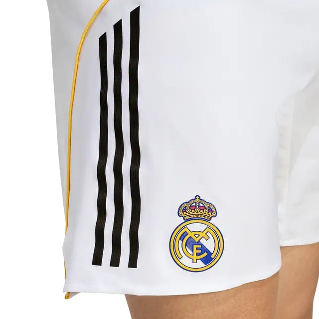 RMCFMP0301_03 | UAE SPORT STORE Close-up of a white Real Madrid jersey featuring three black stripes along the side and the Real Madrid crest near the hem.