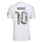 White Real Madrid football jersey shown from the back, with the name Modrić and number 10 filled with a grayscale collage.