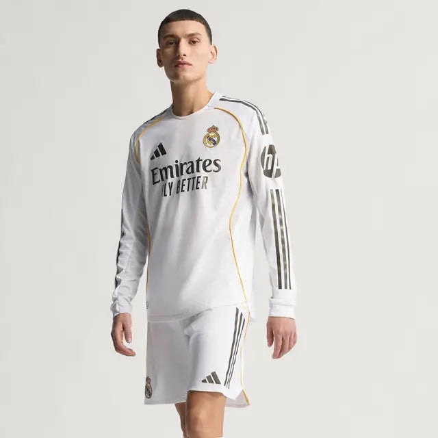 RMCFMZ0902_04 | UAE SPORT STORE Male model wearing Real Madrid white away kit (jersey and shorts) with Emirates sponsor and black stripes, posing in studio.