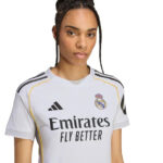 Young woman wearing Real Madrid jersey, white kit with Emirates Fly Better sponsor, facing forward.