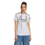 Woman modeling a light gray Real Madrid soccer jersey with Emirates Fly Better sponsor text, facing forward.
