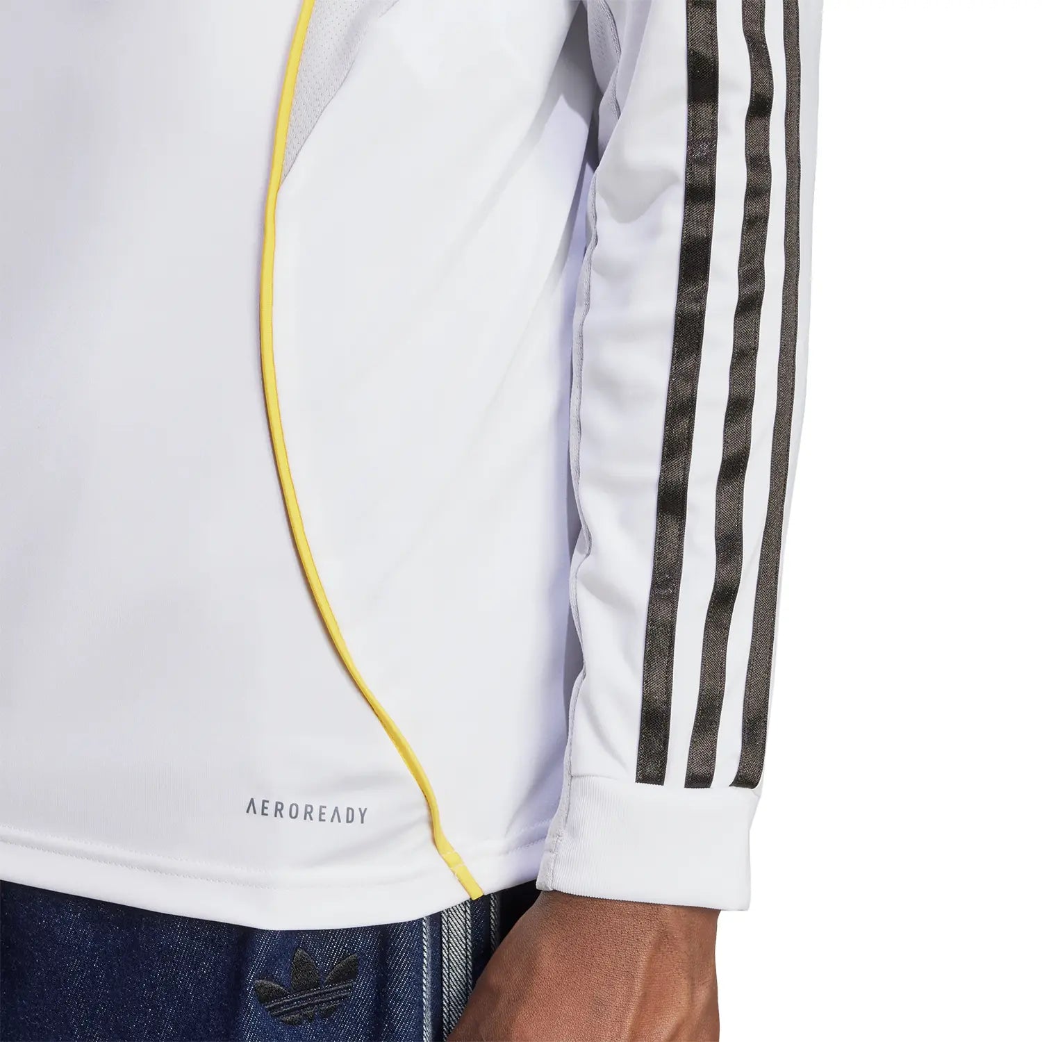 RMCFMZ0905_03 | UAE SPORT STORE Close-up of a white athletic jacket with yellow piping, black striped sleeves, and the 'AEROREADY' logo visible near the hem.