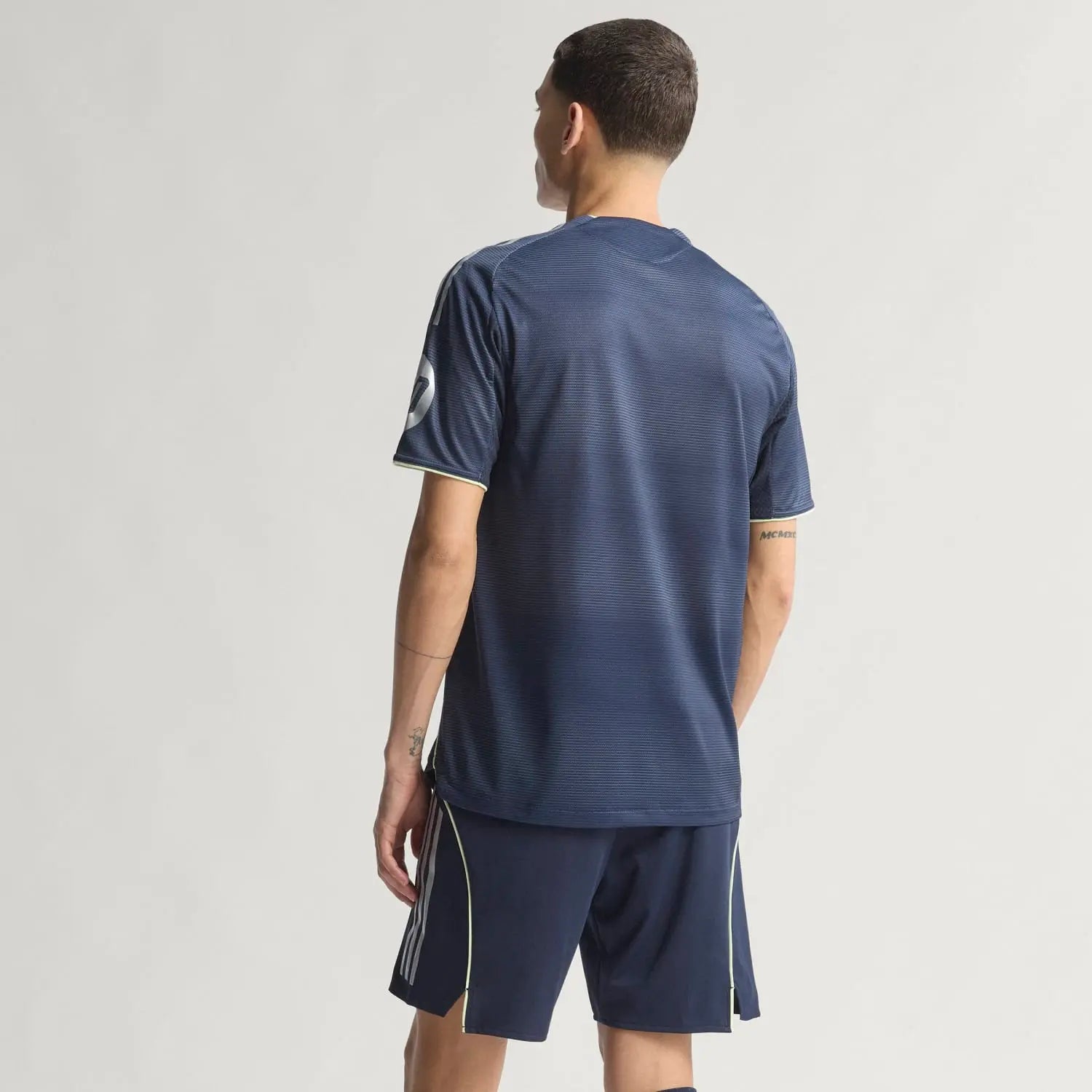 RMCFMZ0920_10 | UAE SPORT STORE Back view of a man in a navy athletic jersey and shorts, standing against a light background, showing short sleeves and subtle piping.
