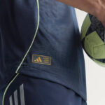RMCFMZ0920_15 | UAE SPORT STORE Close-up of a dark athletic jersey featuring a gold 'AUTHENTIC LICENSED PRODUCT' patch with a neon-green soccer ball nearby.