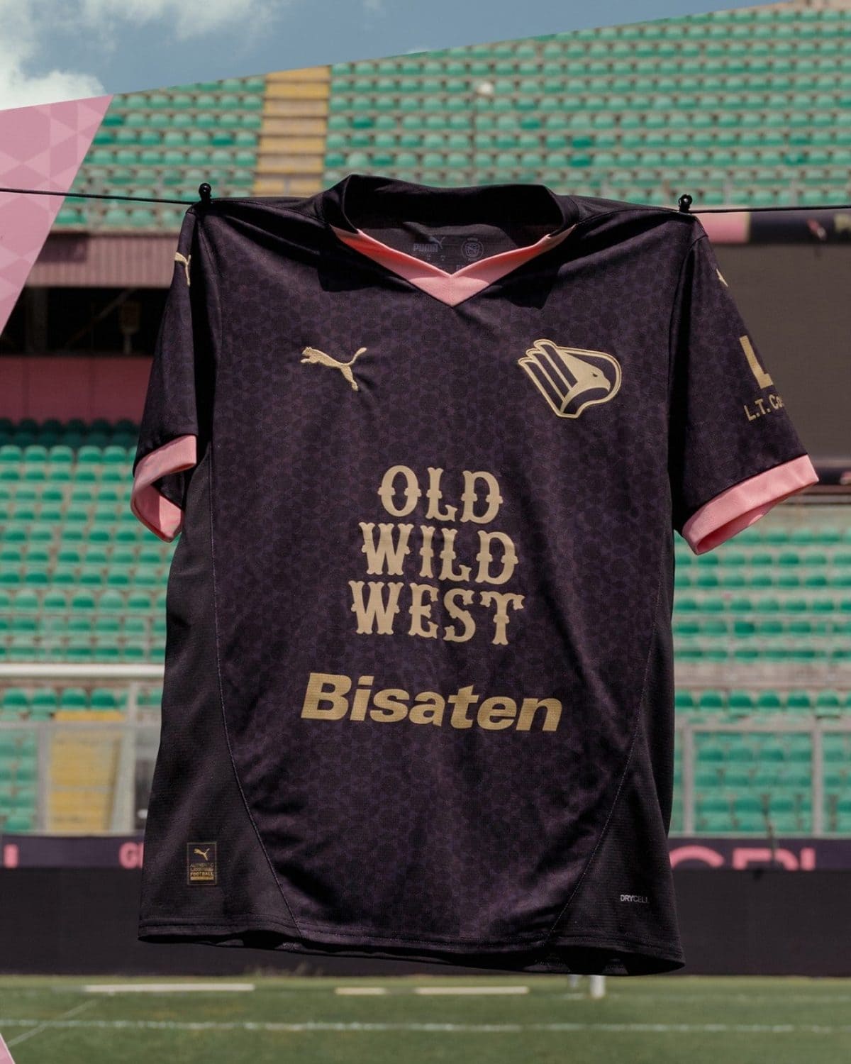 Dark purple football jersey with pink accents hanging on a line in a stadium, reading 'OLD WILD WEST' and 'Bisaten' on the front.