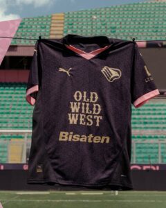Dark purple football jersey with pink accents hanging on a line in a stadium, reading 'OLD WILD WEST' and 'Bisaten' on the front.