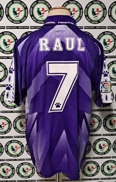 Back view of a purple soccer jersey with the name RAUL and number 7 in white outline, set against a backdrop of circular logos.