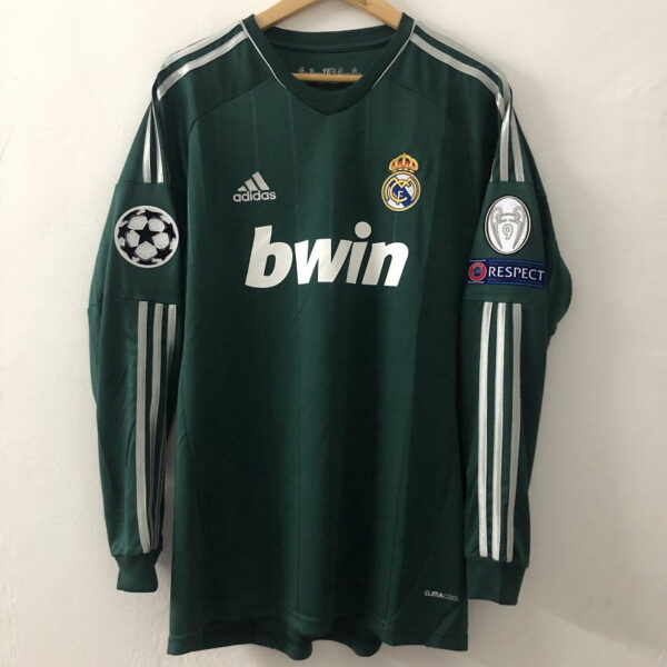 Green Real Madrid football jersey on a hanger featuring the bwin sponsor, adidas logo, club crest, and Champions League sleeve badge with a RESPECT patch on the other sleeve.