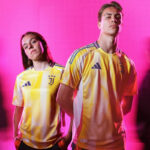 Two young athletes wearing yellow Juventus football jerseys pose against a bright pink background.