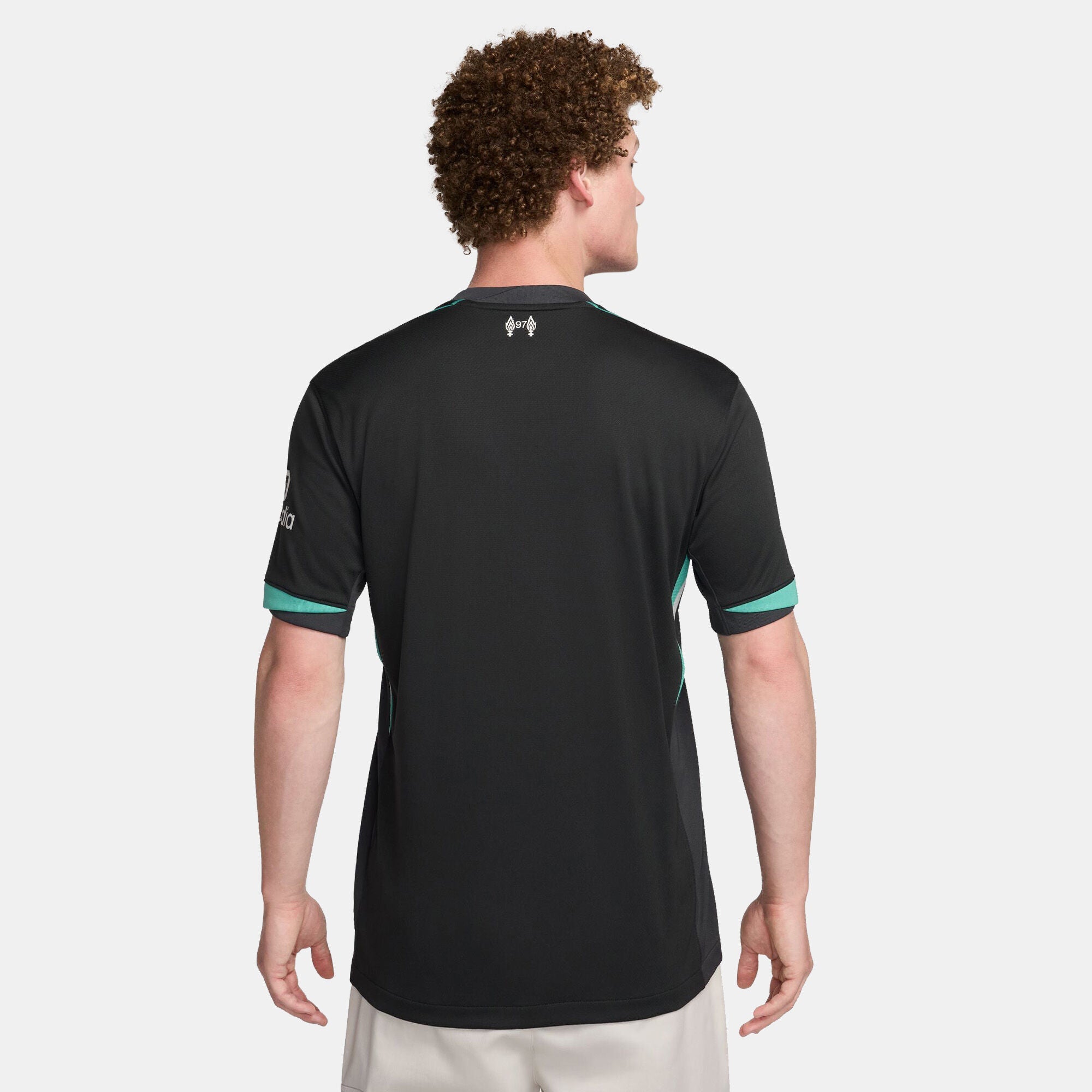 SSS2-NKFN8780_322_196976453442_2_d86acda5-7a1b-47b3-9970-a2f25fc8eb36 | UAE SPORT STORE Back view of a person wearing a black athletic jersey with teal trim on the sleeves and a small white logo at the upper back against a light-gray background.